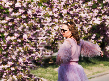 Woman standing by pink flowering plants