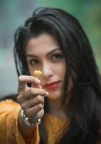 Portrait of beautiful young woman holding small flower