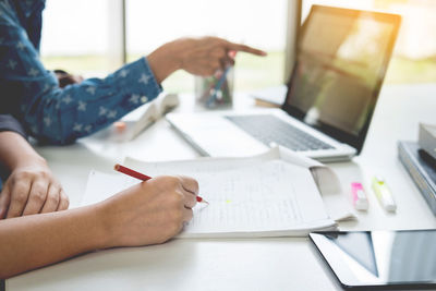 Close-up of woman using laptop on table