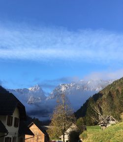 Panoramic view of houses and mountains against blue sky