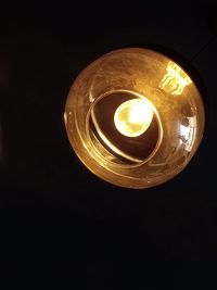 Low angle view of illuminated lamp in darkroom