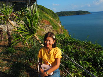 Portrait of smiling girl at park against sea