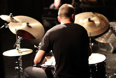 Rear view of man playing drum on stage