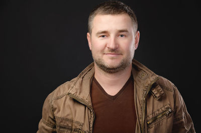 Portrait of young man against black background