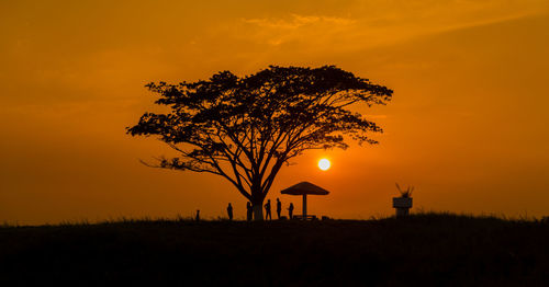 Silhouette tree on field against orange sky