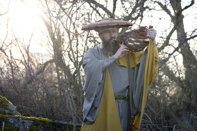 Man holding umbrella standing by tree