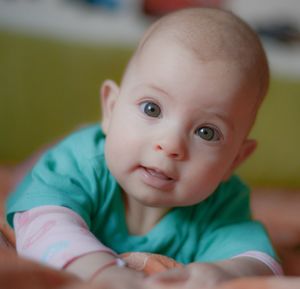 Portrait of cute baby girl lying on bed