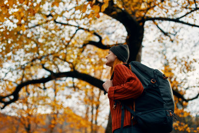 Low angle view of person standing by tree during autumn