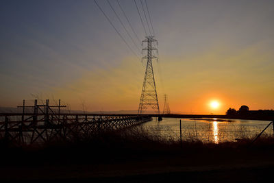 Silhouette electricity pylon against sky during sunset