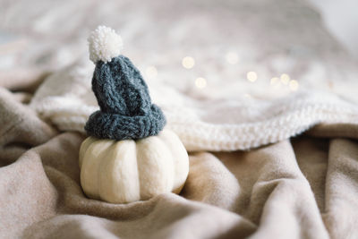 White decorative pumpkin in a decorative knitted hat.