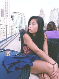 Young woman sitting on car in city