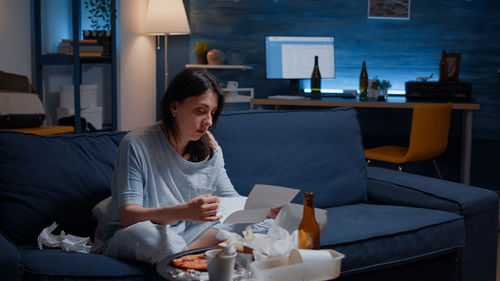 Portrait of young woman using mobile phone while sitting at home