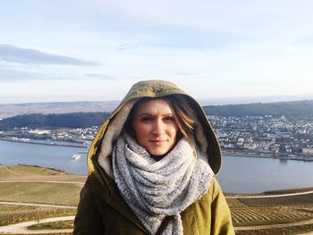 Portrait of woman wearing hooded shirt against town