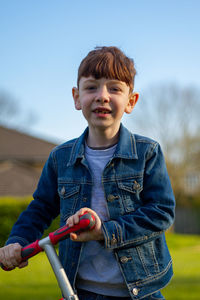 Full length of boy holding camera against sky