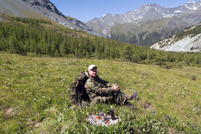 Portrait of man sitting on field against mountains