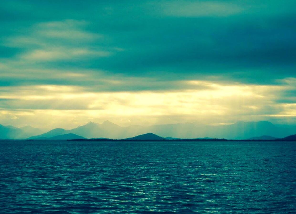 SCENIC VIEW OF SEA AND MOUNTAINS AGAINST BLUE SKY