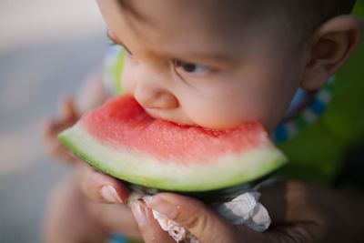 Close-up of cute baby girl eating watermelon outdoors