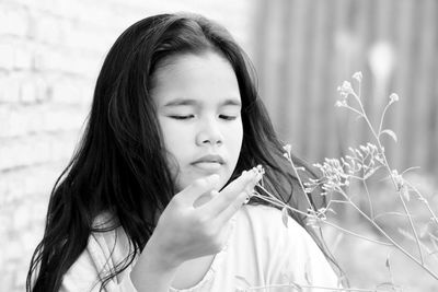 Girl looking at flowering plant in lawn