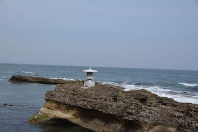 Lighthouse by sea against sky