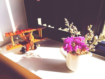 High angle view of flowering in jug by wooden airplane on table
