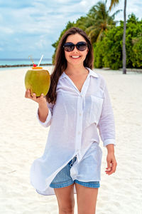 Portrait of young woman standing at beach