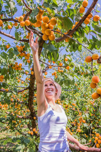 Happy woman with fruits on tree