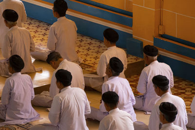 Close up of men praying during funeral ceremony in cao dai temple