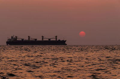 Silhouette ship in sea against sky during sunset