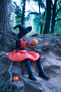 Boy sitting on tree trunk in forest