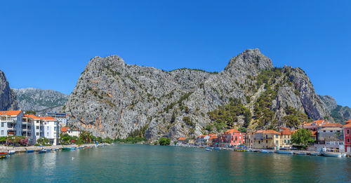 Buildings by mountain against clear blue sky