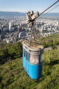 Aerial view of tbilisi town from mountain, georgia. old blue cable car cabin above the town.