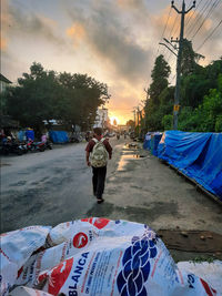 Rear view of man standing on road against sky