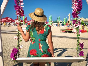 Rear view of woman with on a swing on the beach