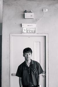 Portrait of young man standing against wall