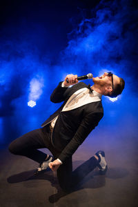 Handsome presenter and showman in a stylish suit with a microphone on stage