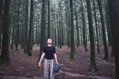 Portrait of man standing against trees in forest