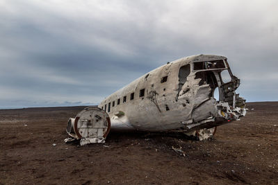 Abandoned airplane at beach against sky