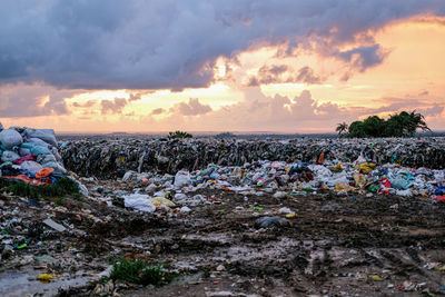 Garbage on land against sky during sunset