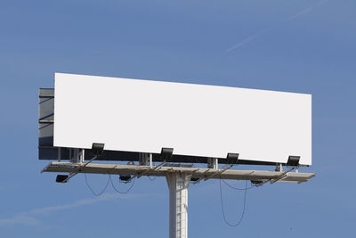 Low angle view of wind turbines against clear blue sky