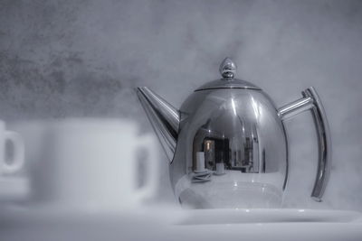 Close-up of tea kettle and cups on table