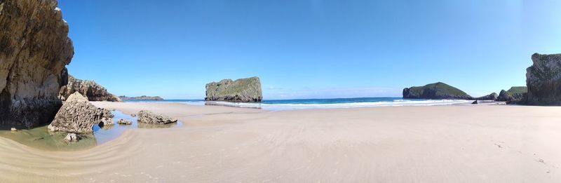 Panoramic view of beach against clear blue sky