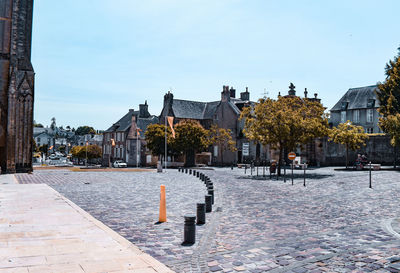 Street amidst trees and buildings against sky