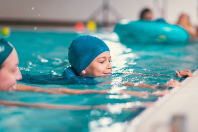 Boy learning to swim in pool with teacher