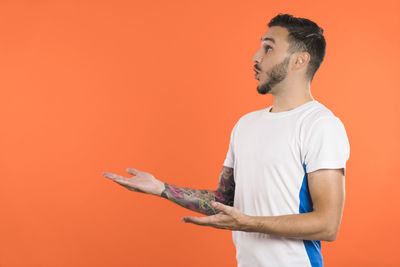 Side view of young man exercising against yellow background