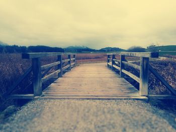 Surface level of wooden bridge against sky