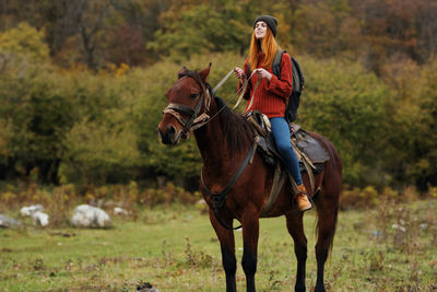 Young woman riding horse on field