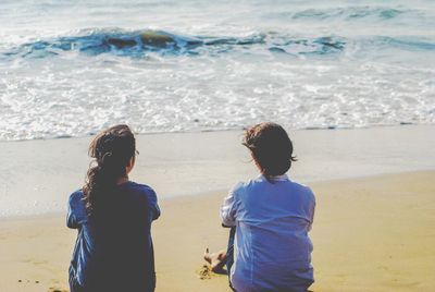 Rear view of friends standing on beach