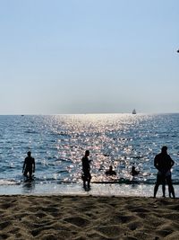 People on beach against clear sky