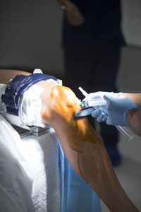 Midsection of doctor injecting syringe on patient leg in operating room
