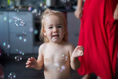 Portrait of shirtless boy looking at bubbles